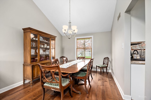 dining space with vaulted ceiling, a notable chandelier, dark wood-type flooring, and baseboards