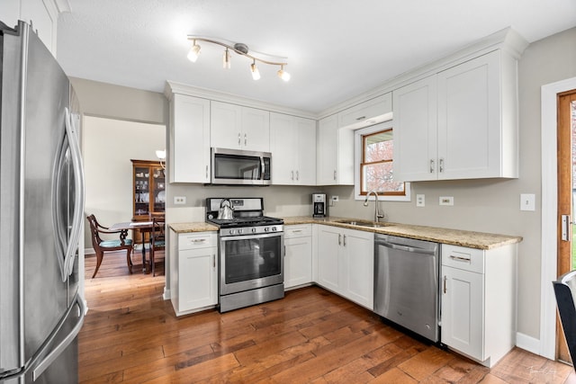 kitchen with white cabinets, dark wood finished floors, stainless steel appliances, and a sink