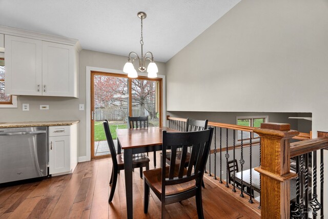 dining room featuring hardwood / wood-style flooring, baseboards, an inviting chandelier, and vaulted ceiling