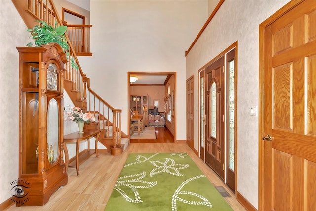 entrance foyer with a towering ceiling, wood finished floors, stairway, and baseboards
