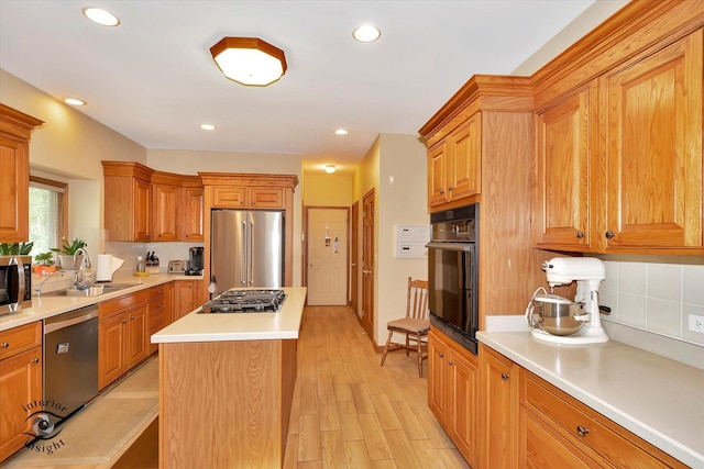 kitchen featuring appliances with stainless steel finishes, a sink, tasteful backsplash, light countertops, and a kitchen island