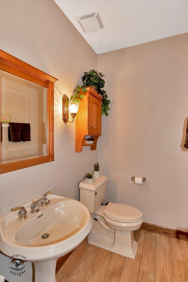 bathroom with toilet, wood finished floors, a sink, and baseboards