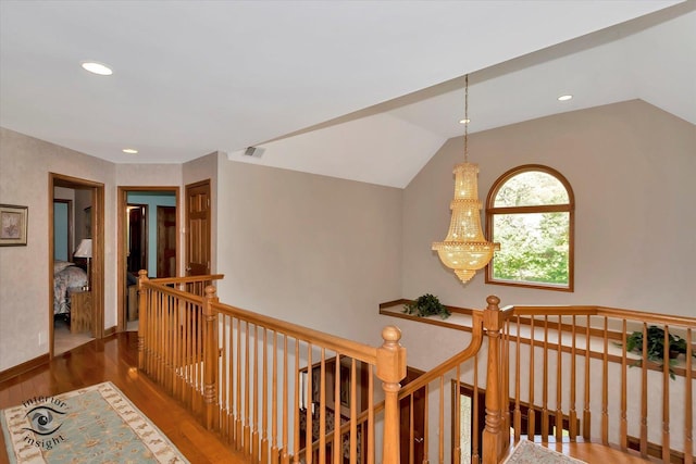 hallway with an upstairs landing, wood finished floors, recessed lighting, a chandelier, and vaulted ceiling