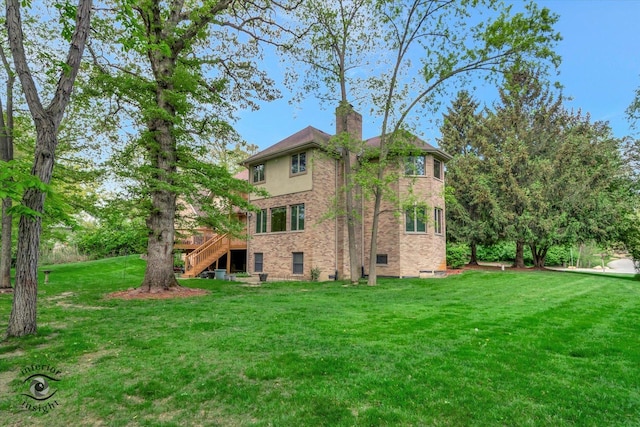 rear view of house featuring stairs, a yard, a chimney, and a deck
