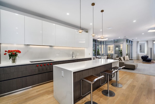 2035 N Orleans St Unit 2N, Chicago, IL 60614 - kitchen featuring modern cabinets, light wood-type flooring, white cabinetry, a sink, and a breakfast bar area