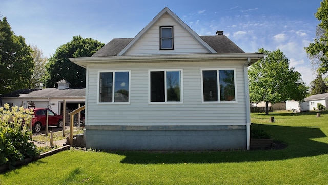 rear view of house featuring roof with shingles and a yard