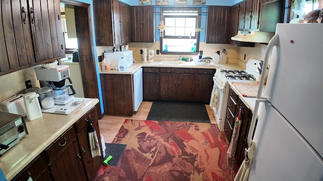 kitchen featuring a sink, under cabinet range hood, white appliances, and light countertops