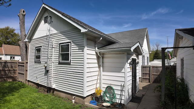 view of side of home featuring fence and a shingled roof