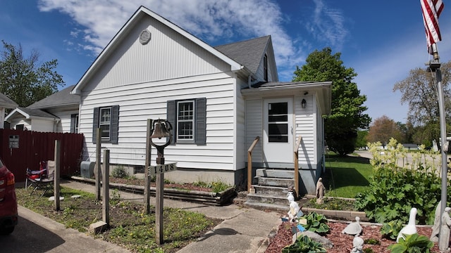 bungalow with entry steps, fence, and roof with shingles