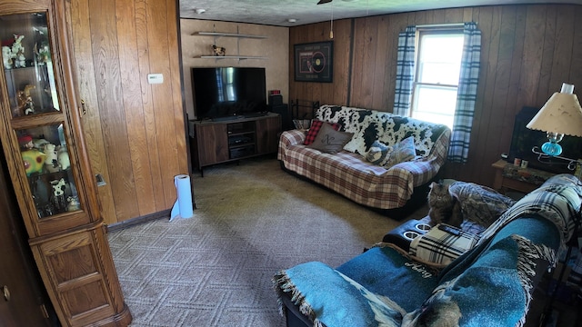 carpeted living area with a ceiling fan and wood walls