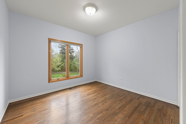 unfurnished room featuring visible vents, wood finished floors, and baseboards