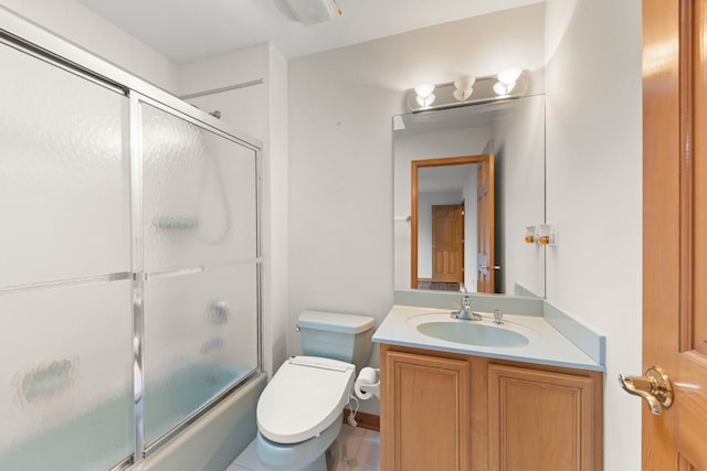 bathroom featuring bath / shower combo with glass door, tile patterned flooring, vanity, and toilet