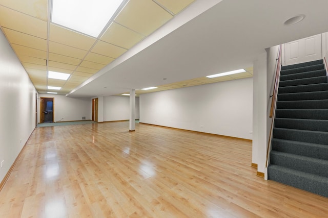 finished below grade area featuring stairway, baseboards, and wood finished floors