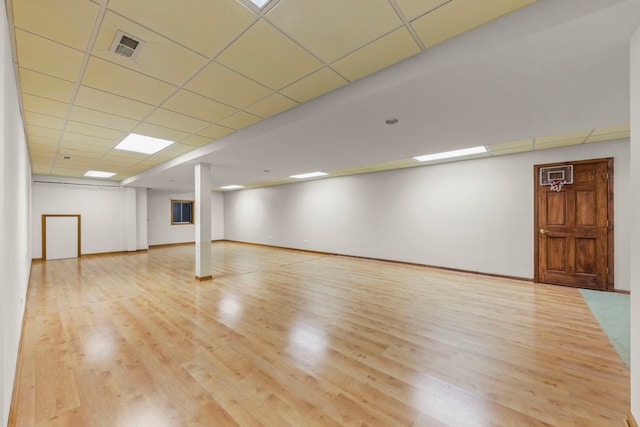 finished basement with baseboards, a drop ceiling, wood finished floors, and visible vents