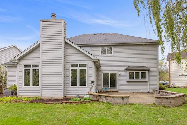rear view of property with a chimney, a yard, central AC unit, and a patio