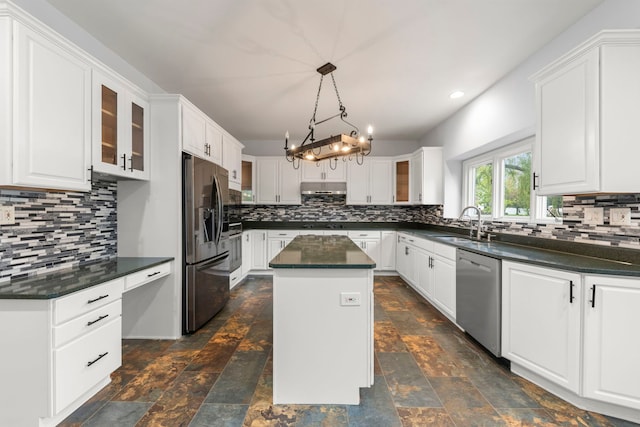 kitchen with under cabinet range hood, white cabinetry, a kitchen island, backsplash, and appliances with stainless steel finishes