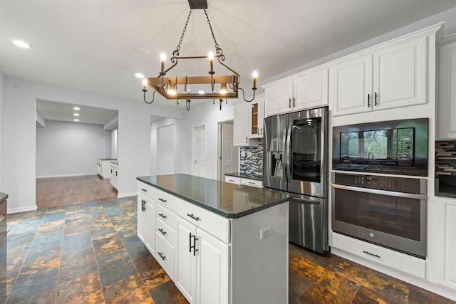 kitchen featuring dark countertops, appliances with stainless steel finishes, tasteful backsplash, and stone finish floor
