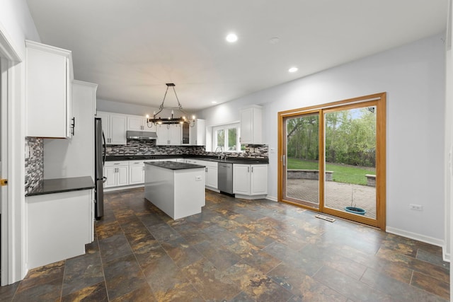kitchen with dark countertops, stainless steel appliances, an inviting chandelier, and backsplash