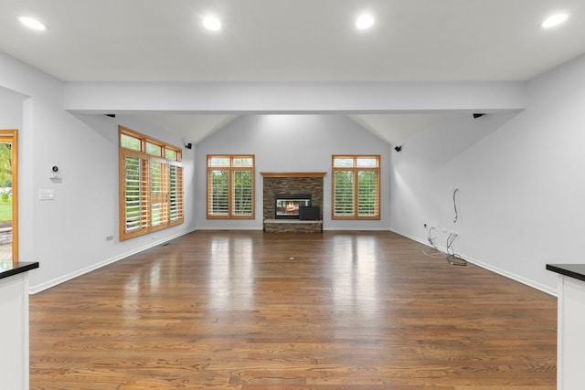 unfurnished living room with lofted ceiling, recessed lighting, a healthy amount of sunlight, and wood finished floors