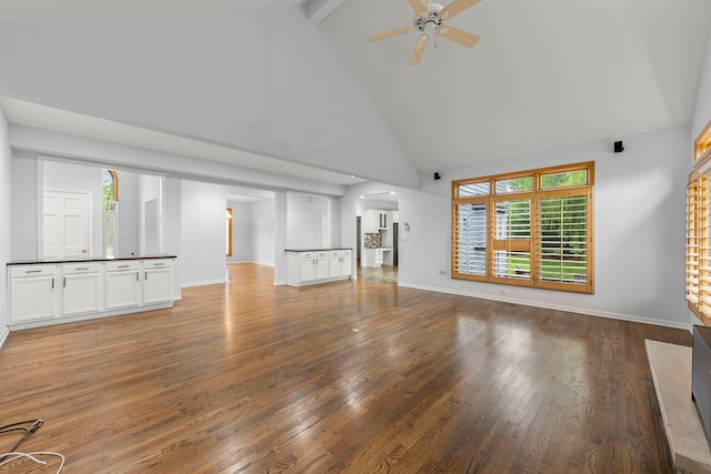 unfurnished living room featuring wood finished floors, a ceiling fan, high vaulted ceiling, beam ceiling, and baseboards