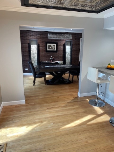 dining area with light wood-type flooring, visible vents, crown molding, and baseboards