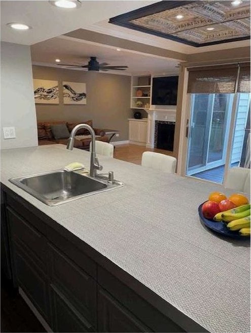 kitchen with open floor plan, a fireplace, light countertops, and a sink