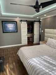 bedroom with a barn door, baseboards, wood finished floors, and recessed lighting