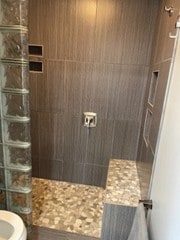 full bath with a tile shower and toilet