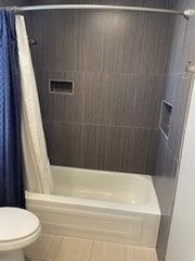 full bathroom featuring shower / tub combo, toilet, and tile patterned flooring