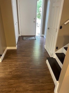 hallway featuring dark wood finished floors, stairs, and baseboards