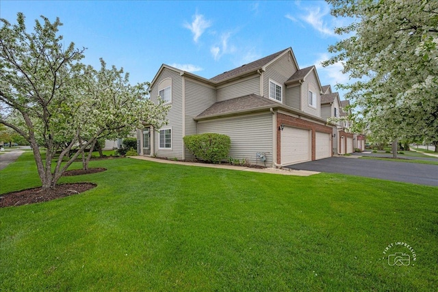 view of side of home featuring driveway, an attached garage, a yard, and a shingled roof