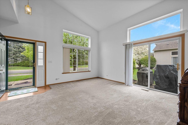 carpeted entrance foyer featuring high vaulted ceiling and baseboards