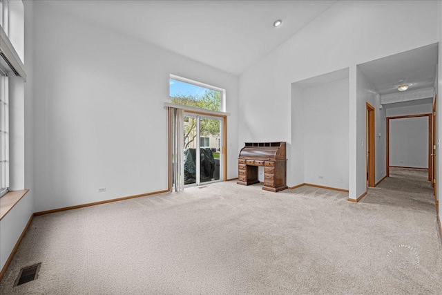 unfurnished living room with carpet flooring, baseboards, and high vaulted ceiling