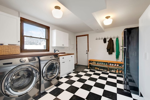 laundry area with washing machine and dryer, cabinet space, a sink, and dark floors