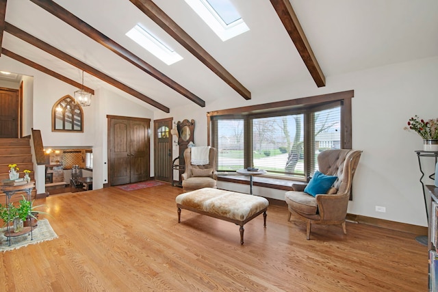 sitting room with an inviting chandelier, vaulted ceiling with skylight, wood finished floors, and baseboards