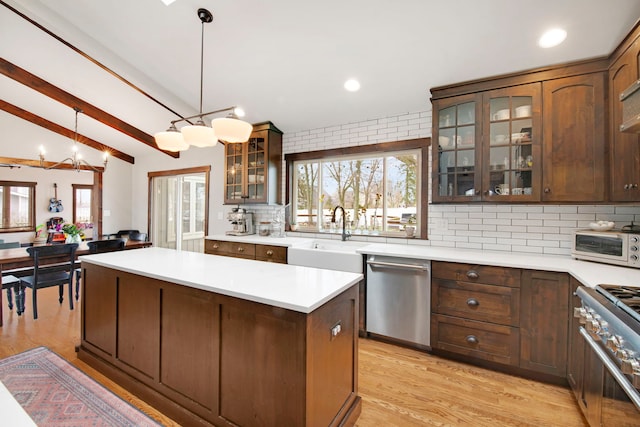 kitchen with a center island, a sink, backsplash, light countertops, and appliances with stainless steel finishes