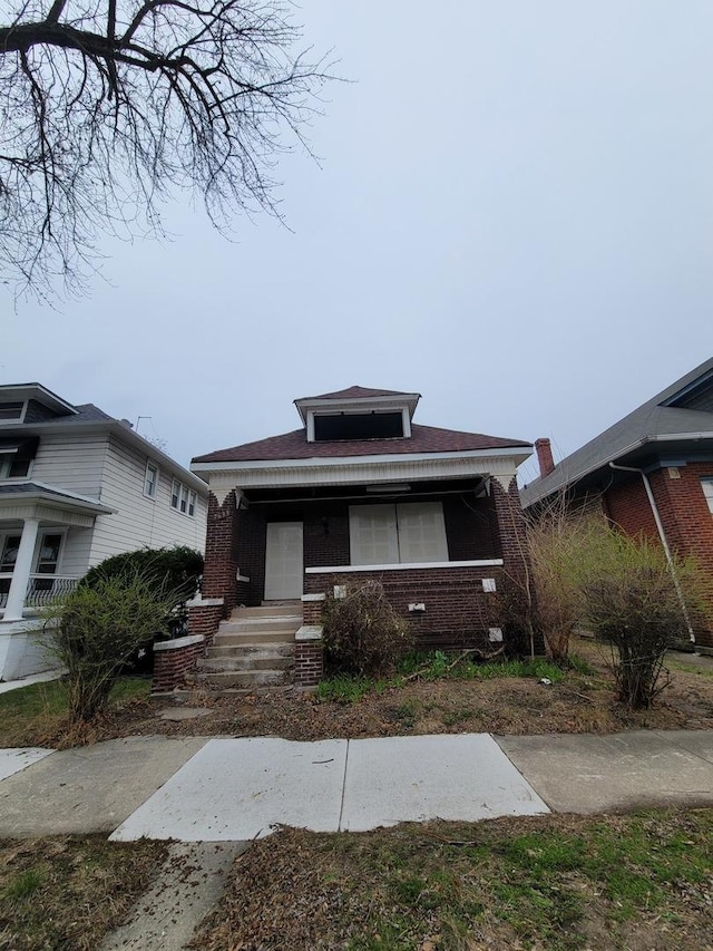 bungalow with covered porch and brick siding