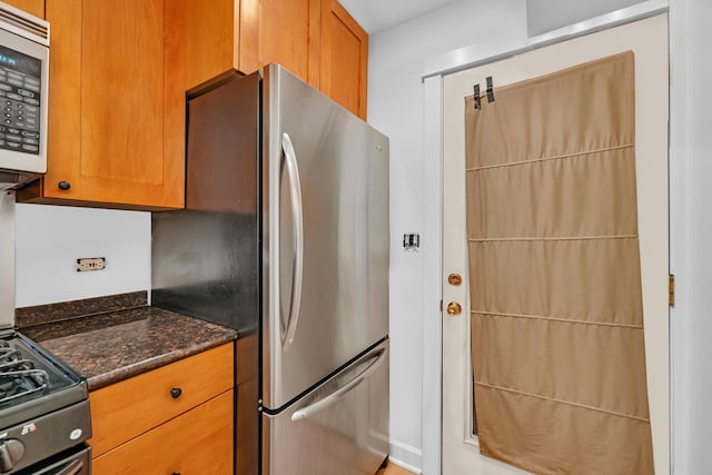 5014 N Oakley Ave Unit G, Chicago, IL 60625 - kitchen featuring dark stone counters, appliances with stainless steel finishes, and brown cabinetry