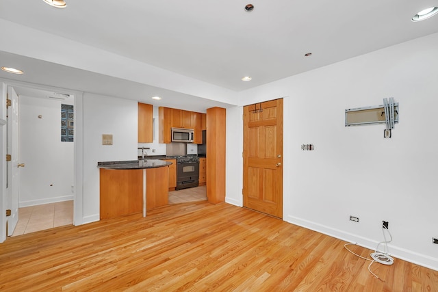 5014 N Oakley Ave Unit G, Chicago, IL 60625 - kitchen featuring dark countertops, stainless steel microwave, black gas range, and light wood-style floors
