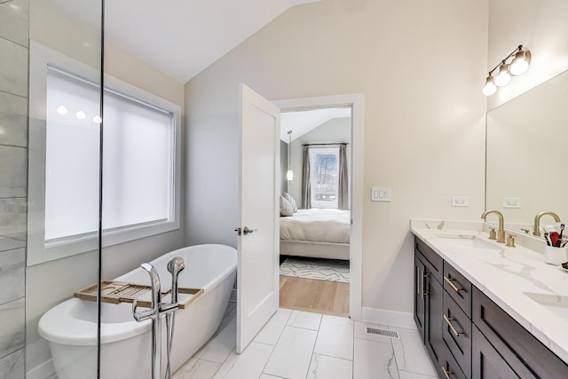 full bathroom with ensuite bathroom, a freestanding tub, a sink, double vanity, and vaulted ceiling