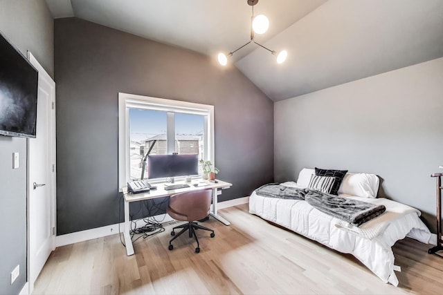 bedroom featuring baseboards, wood finished floors, and lofted ceiling