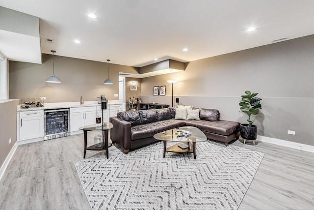 living area with visible vents, baseboards, indoor wet bar, light wood-type flooring, and wine cooler