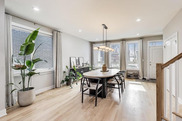 dining area with light wood-style floors, visible vents, and stairs