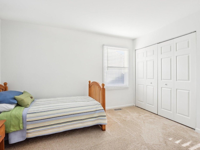 bedroom with baseboards, visible vents, carpet, and a closet