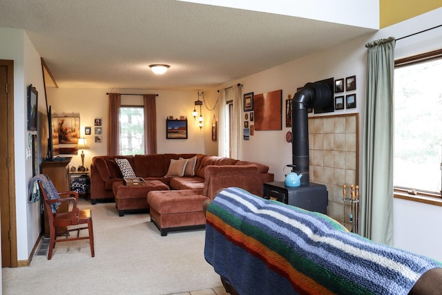 bedroom featuring light carpet, a wood stove, and a textured ceiling