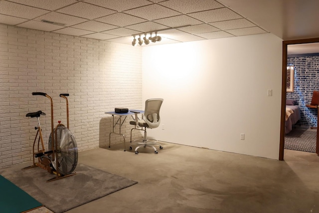 interior space with a paneled ceiling, brick wall, and carpet floors