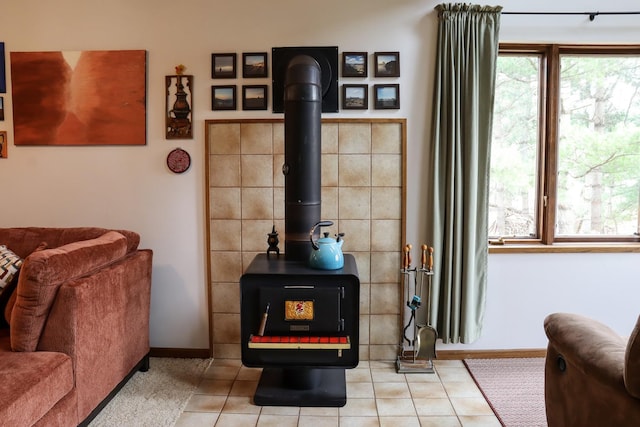living area with tile patterned floors, a wood stove, and baseboards