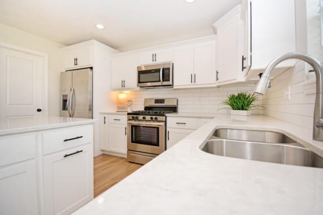 kitchen featuring white cabinets, light countertops, a sink, and appliances with stainless steel finishes