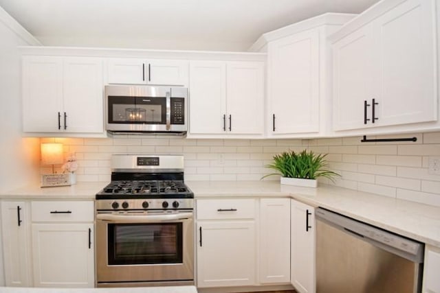 kitchen featuring white cabinets, appliances with stainless steel finishes, tasteful backsplash, and light countertops