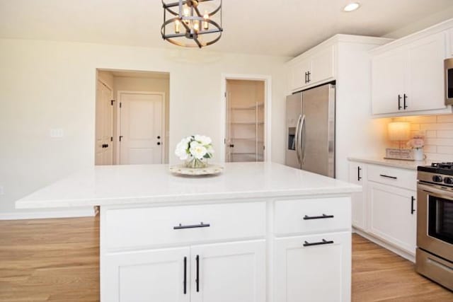 kitchen with white cabinets, an inviting chandelier, light wood-style floors, light countertops, and appliances with stainless steel finishes